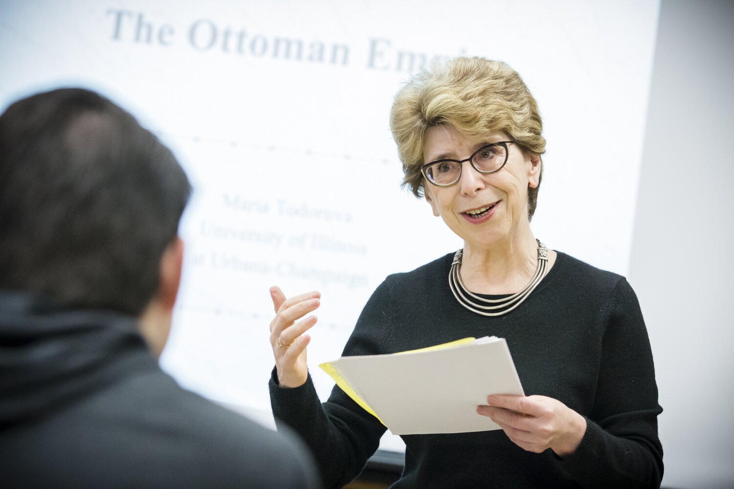 Smiling female professor lecturing in classroom.